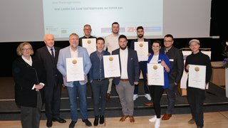 News Gruppe von Personen mit Urkunden bei einer Preisverleihung vor Leinwand