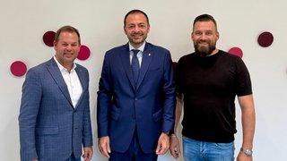 News Drei Männer stehen vor weißer Wand mit roten Punkten