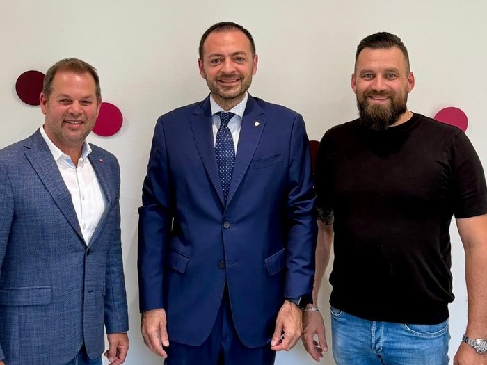 Positive Aussprache über Schlachthof Bozen – neue Perspektiven auch für Ausbildung im Metzgerhandwerk Drei Männer stehen vor weißer Wand mit roten Punkten