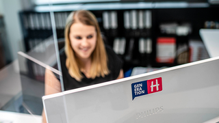 News Frau arbeitet am Computer in einem Büro mit Akten im Hintergrund