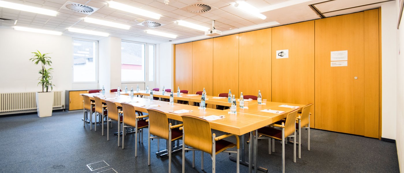 Affitto aule seminari Sala conferenze luminosa con tavolo, sedie e bottiglie d'acqua pronte