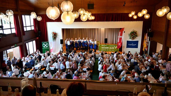 Althandwerker/innen treffen sich in Seis am Schlern Große Versammlung mit Menschen, die bei einem Konzert und Essen in einer Halle teilnehmen