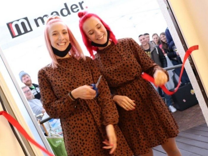 Mutig und innovativ trotz Corona Zwei Frauen in braunen Kleidern schneiden ein rotes Band durch bei Eröffnung