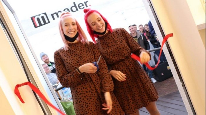 Mutig und innovativ trotz Corona Zwei Frauen in braunen Kleidern schneiden ein rotes Band durch bei Eröffnung