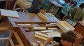 Mit Holz, Wasser & Handwerksfreude: Die KidsAcademy ist in Bruneck angekommen Kinder bearbeiten Holzstücke in einer Werkstatt an Holzbänken.