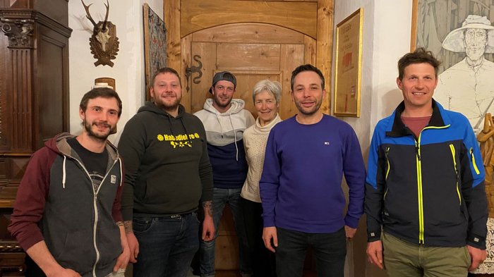 Beständigkeit beim Handwerk in Barbian Sechs Personen stehen vor einer Holztür in einem gemütlichen Raum