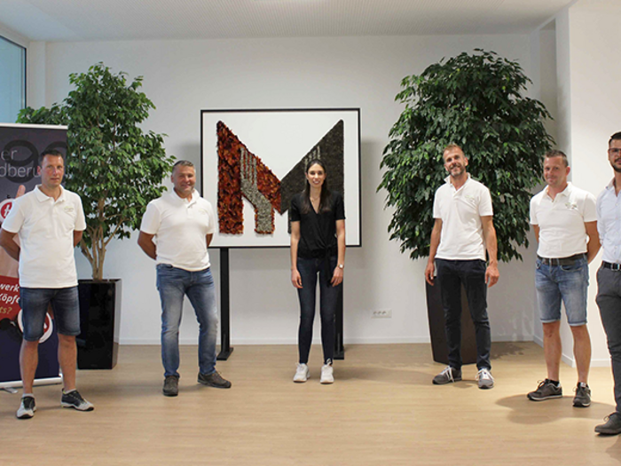 Startschuss für die neue Junghandwerker Ortsgruppe Tschögglberg Gruppenfoto von acht Personen in hellem Büro mit Pflanzen und Kunstwerk