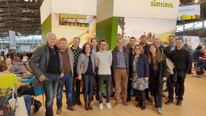 Una delegazione sudtirolese visita la fiera bavarese "Zukunft Handwerk" Gruppo di persone davanti allo stand Südtirol in una sala esposizioni