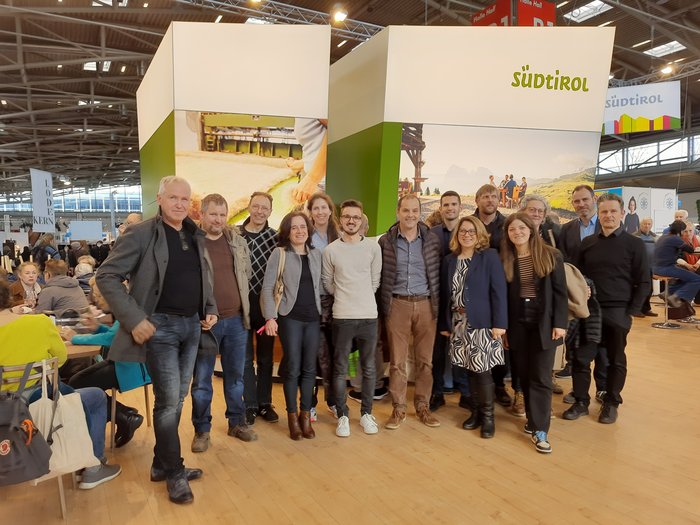 Una delegazione sudtirolese visita la fiera bavarese "Zukunft Handwerk" Gruppo di persone davanti allo stand Südtirol in una sala esposizioni
