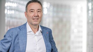 News Mann im blauen Anzug vor unscharfem Hintergrund