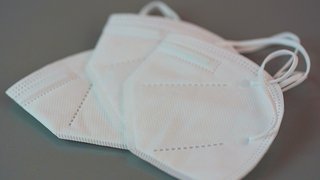 News Drei weiße FFP2-Masken auf grauem Untergrund