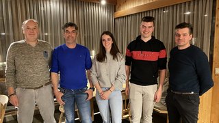 News Fünf Personen stehen lächelnd vor einem Fenster mit Vorhängen in einem Holzraum