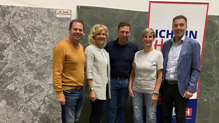 lvh-Bezirksversammlung Burggrafenamt: Handwerk im Fokus Fünf Personen posieren vor Steinplatten und einem Michelinhot Banner