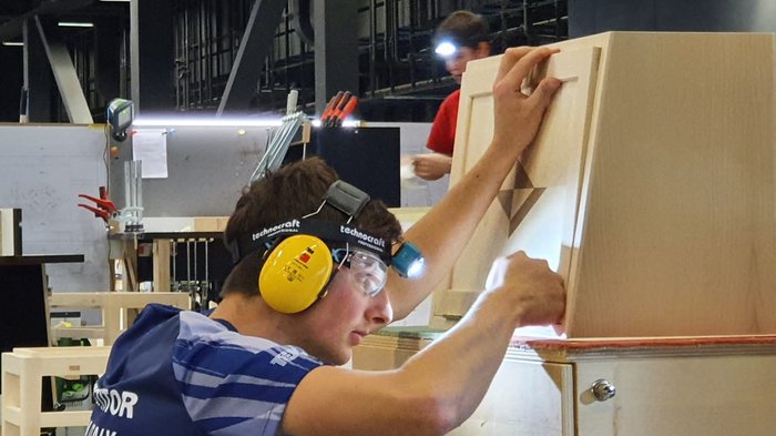 WorldSkills 2022 Special Edition: Zimmerer Marcel Bolego holt Silbermedaille Handwerker mit Schutzbrille und Kopflampe arbeitet an Holzprojekt in Werkstatt
