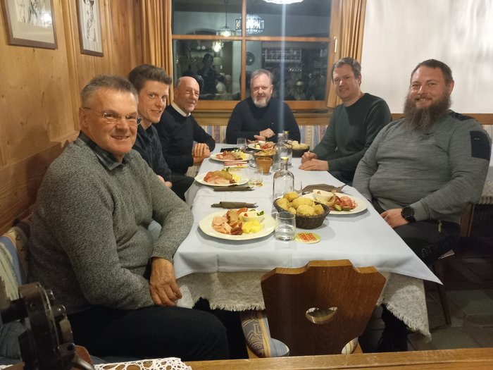 Villnöss: Norbert Lang bleibt lvh-Ortsobmann Sechs Männer sitzen an einem Tisch mit Speisen und Getränken in einem gemütlichen Raum