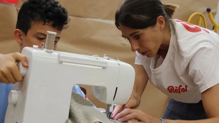 Kids-Academy 2024: Ein Sommer voller Kreativität und Handwerk Frau zeigt Junge das Nähen mit einer Nähmaschine