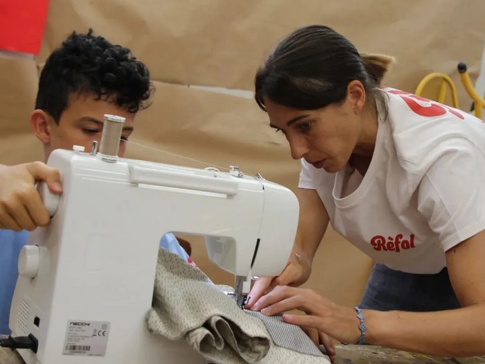 Kids-Academy 2024: Ein Sommer voller Kreativität und Handwerk Frau zeigt Junge das Nähen mit einer Nähmaschine