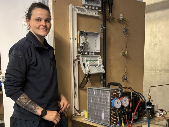 Basta provarci: Julia Pföstl trova il suo posto nella refrigerazione Donna accanto a un impianto tecnico aperto con tubi e strumenti di misurazione