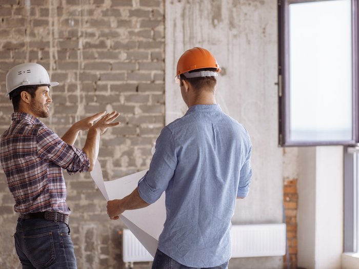 Wirtschaftsbarometer Baugewerbe: Gutes Jahr 2023, Ungewissheit für 2024 Zwei Bauarbeiter mit Helmen besprechen Baupläne in einem Rohbau