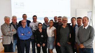 News Gruppenfoto von 14 Personen in einem Besprechungsraum vor einem Projektorbildschirm