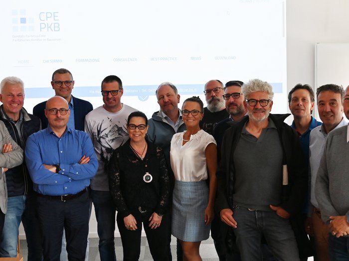 Pietra miliare del partenariato sociale: l'Alto Adige pianifica un centro di competenza per la sicurezza sul lavoro nel settore edile Foto di gruppo di 14 persone in una sala riunioni davanti a un proiettore