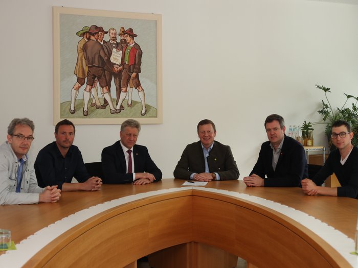 „EU-Entwaldungsverordnung gefährdet nachhaltige Waldbewirtschaftung“ Sechs Männer sitzen an einem runden Holztisch in einem Besprechungsraum mit Gemälde an der Wand