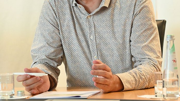 Wohnen muss leistbar sein! Herausforderungen und Lösungsansätze in Südtirol Mann spricht und gestikuliert während eines Meetings am Tisch