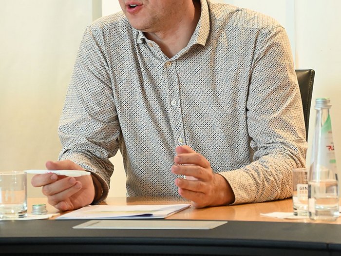 Wohnen muss leistbar sein! Herausforderungen und Lösungsansätze in Südtirol Mann spricht und gestikuliert während eines Meetings am Tisch