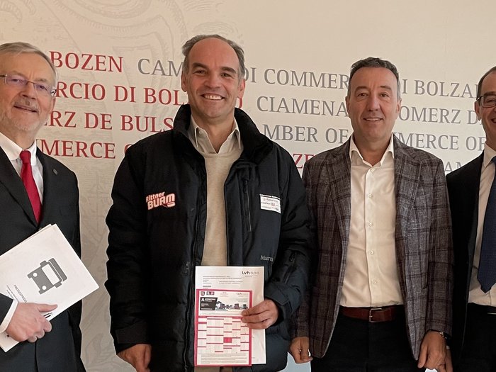 Austausch zu Verkehrs- und Transportproblemen: Wirtschaft fordert gemeinsame Lösungen Vier lächelnde Männer in formeller und legerer Kleidung vor einer Handelskammer-Wand.