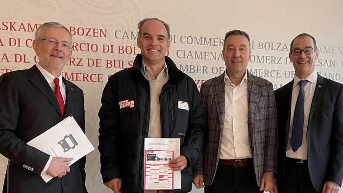 Austausch zu Verkehrs- und Transportproblemen: Wirtschaft fordert gemeinsame Lösungen Vier lächelnde Männer in formeller und legerer Kleidung vor einer Handelskammer-Wand.