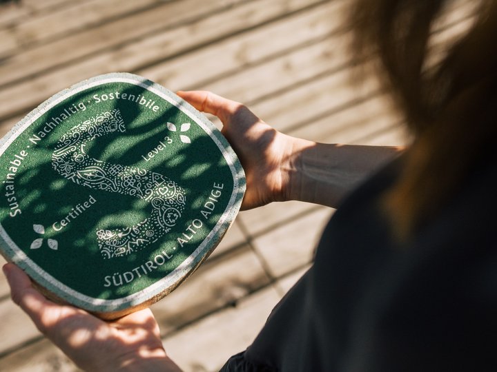 Das Nachhaltigkeitslabel Südtirol Person hält nachhaltiges zertifiziertes Produkt aus Südtirol in den Händen