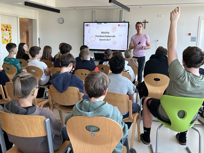 Einblicke in den Berufsalltag Junger Mann gibt Unterricht zu Handwerksberufen vor einer Gruppe Schüler