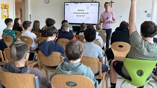 News Junger Mann gibt Unterricht zu Handwerksberufen vor einer Gruppe Schüler