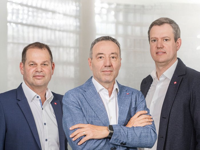 Verkehrssituation rund um Bozen: Die Wirtschaft kann nicht länger warten! Drei Männer in Anzügen stehen vor einem hellen Bürofenster