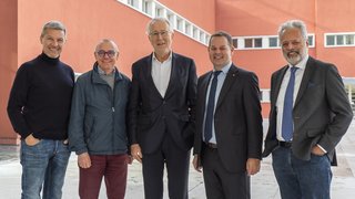 © Eurac Research/Annalie Bortolotti Fünf lächelnde Männer vor rotem Gebäude im Freien