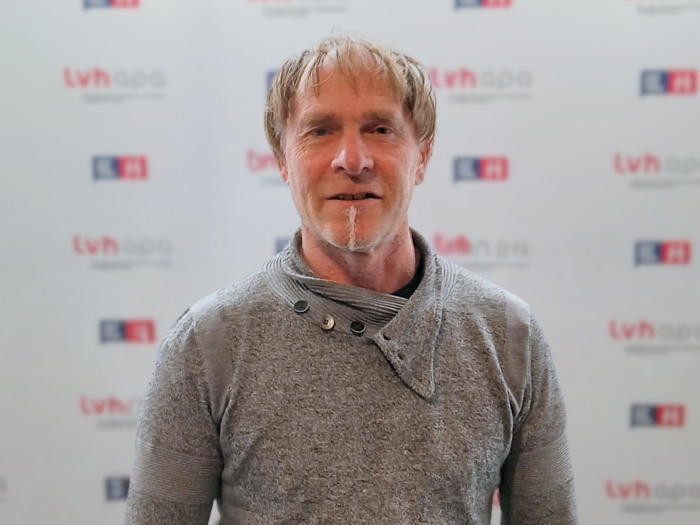 Zwei engagierte Funktionäre bekleiden neue Ämter Mann mit grauem Pullover vor TVH Apa Werbewand