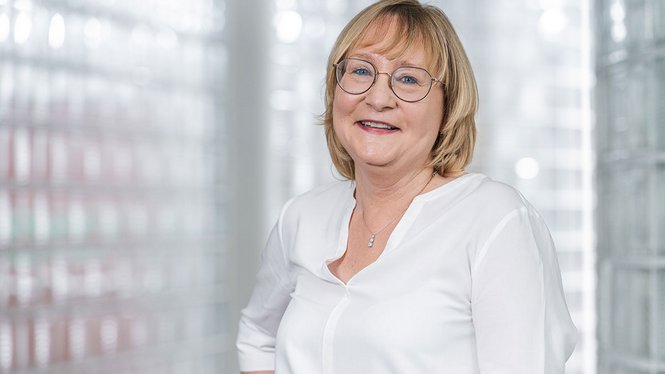 Ritratto di una donna anziana sorridente con occhiali su sfondo chiaro