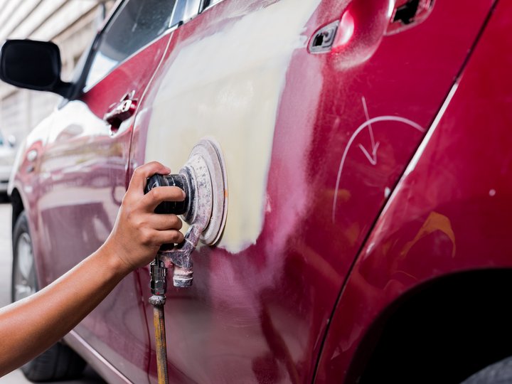 Karosserietechniker Hand schleift die Autotür mit Schleifmaschine für Lackreparatur