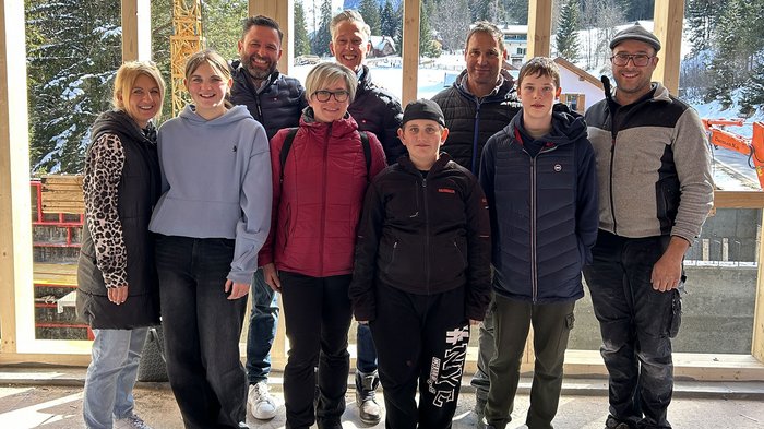 Berufsorientierung in Partschins: Jugendliche entdecken Handwerk und Gastgewerbe Gruppe von neun Personen vor einem Holzrahmen mit verschneiten Bergen im Hintergrund