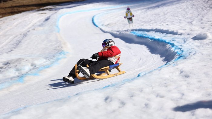 Südtirols erster Handwerker-Snowpark eingeweiht Person fährt mit Schlitten auf einer verschneiten, kurvigen Bahn