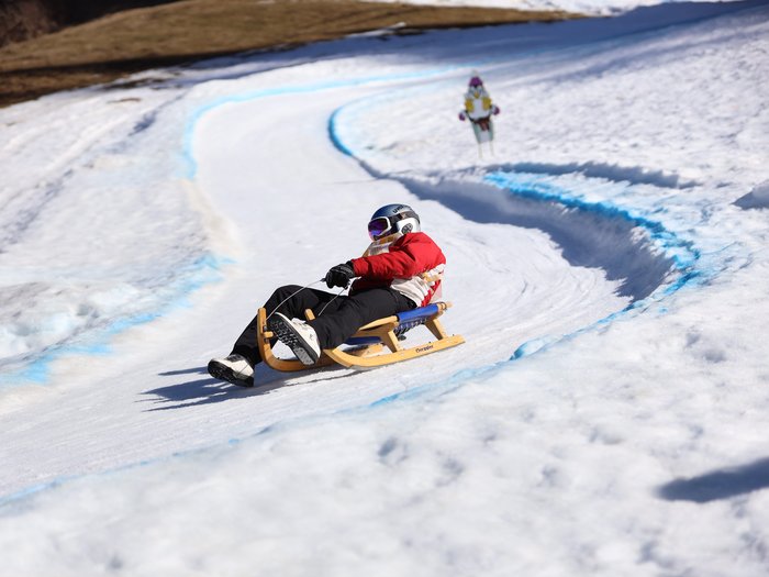 Südtirols erster Handwerker-Snowpark eingeweiht Person fährt mit Schlitten auf einer verschneiten, kurvigen Bahn