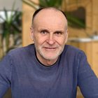 Bau- und Galanteriespengler Porträt eines lächelnden älteren Mannes in blauem Pullover vor neutralem Hintergrund