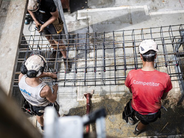 Patente a crediti: proposta di proroga Operai edili con caschi montano armatura in acciaio in cantiere vista dallalto