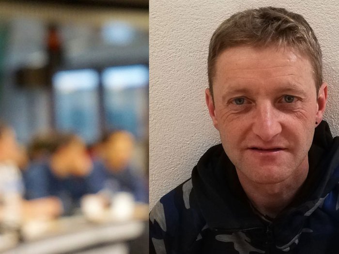 „Macht eure Leute glücklich“ Porträt eines lächelnden Mannes vor verschwommenem Hintergrund mit Menschen