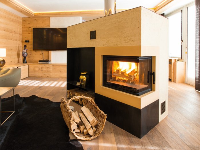 Nonostante il freddo: non sovraccaricare le stufe Stufa moderna a legna con fuoco acceso in un soggiorno accogliente