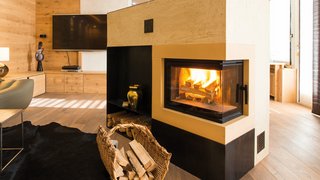 News Moderner Holzofen mit brennendem Feuer in gemütlichem Wohnzimmer