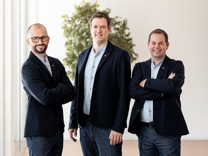 Der Appell des lvh-Chefs: „Nutzen wir die Chance der Massentests, um die Wirtschaft wieder komplett hochfahren zu können!“ Drei Männer in Anzügen stehen nebeneinander in einem modernen Büro