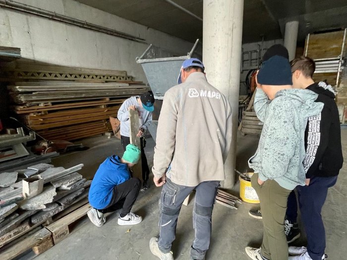 Die Handwerks- und Gastbetriebe von Schenna im Fokus Gruppe junger Leute in Baustelle mit Betonmischer und Bauholz