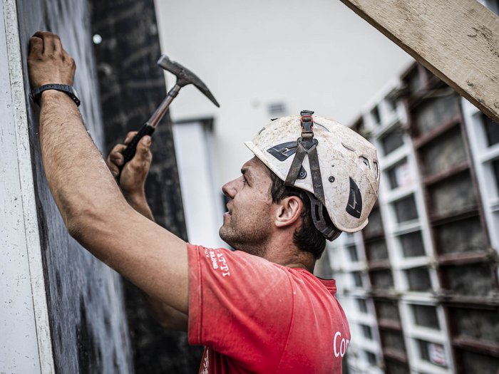 Edilizia: gli addetti ai lavori di lvh.apa sono preoccupati Operaio edile con casco che lavora con un martello su una parete