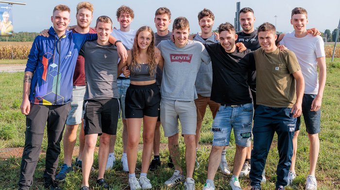 WorldSkills 2024 in Lyon am Start Gruppe junger Menschen draußen stehen zusammen und lächeln auf einer Wiese